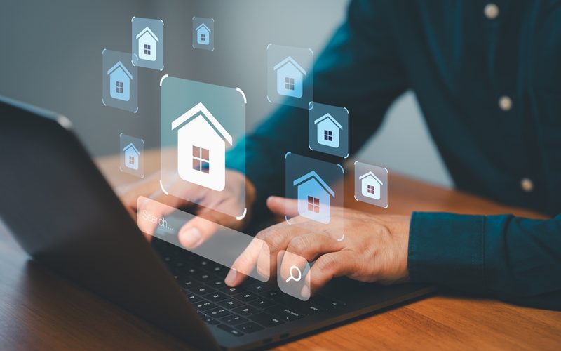 Hands typing on a laptop with virtual home search icons