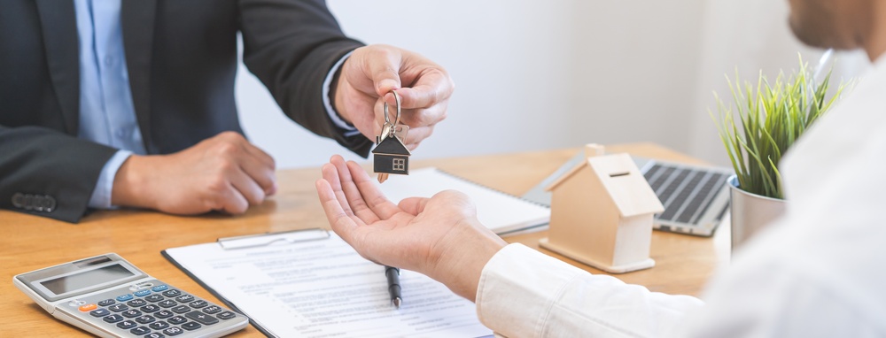 Close up of agent giving keys to new homeowner